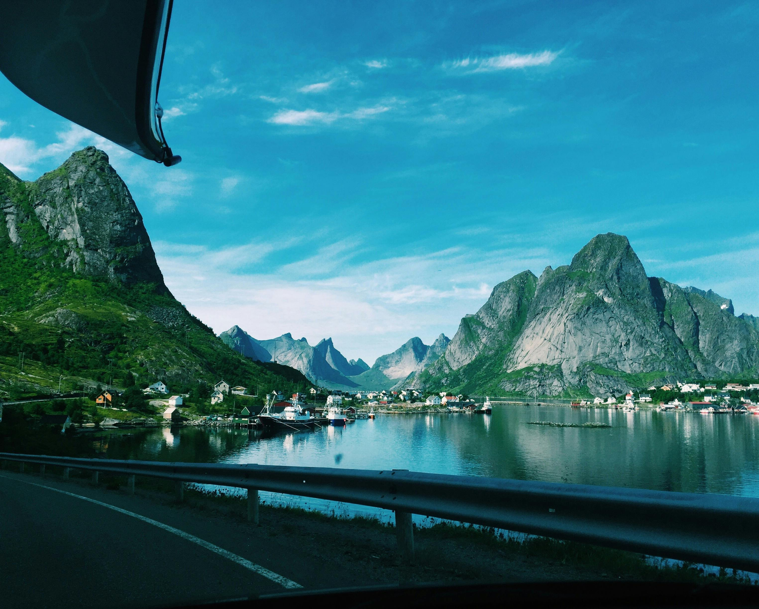 Utsikt over en kystlandsby i Lofoten med bratte fjell og blått vann